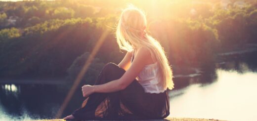 woman sitting on brown surface watching at body of water